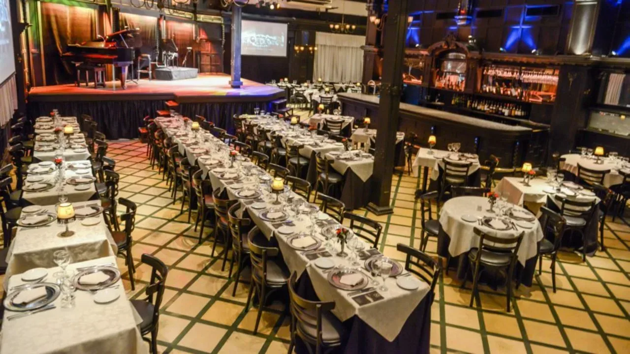 Long tables laid with white linen and glassware in El Querandi's checkered-floor hall before the show
