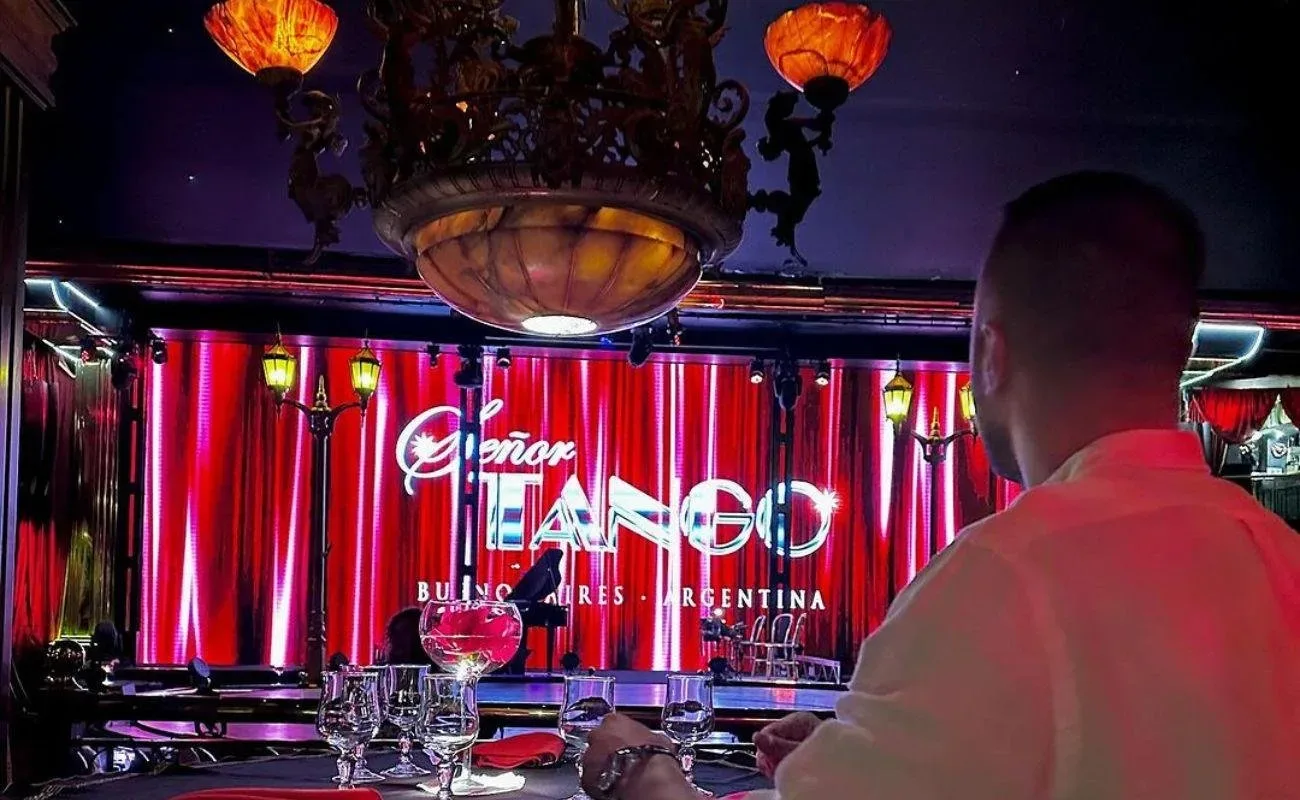 Senor Tango's cabaret hall with red drapes and a chandelier above tables set for dinner